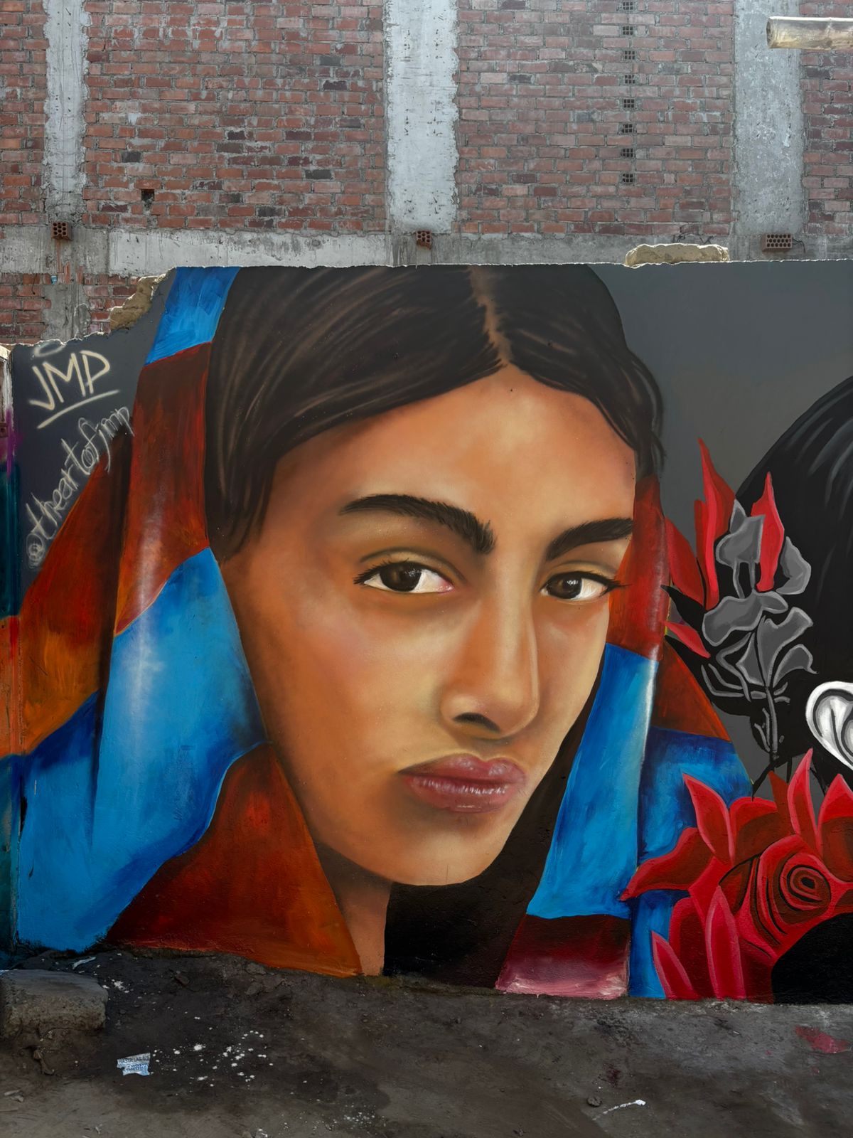 Mural de retrato en tonos azules y rojos sobre pared de ladrillo